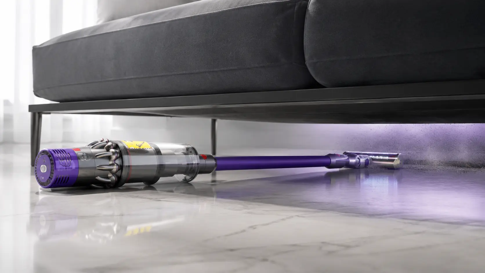 Dyson cordless vacuum cleaning beneath a sofa