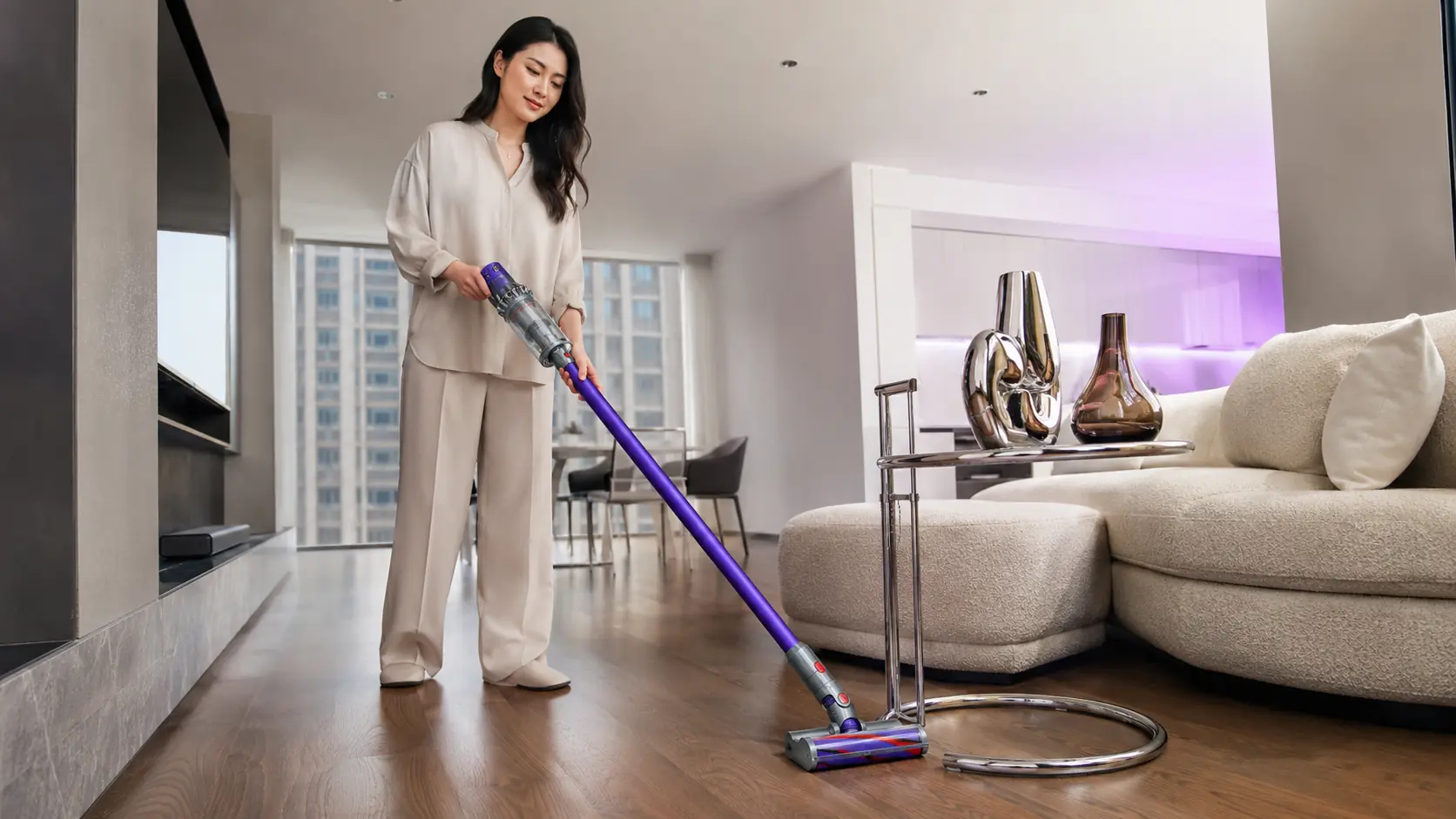 Woman using a Dyson cordless vacuum in a bright living room