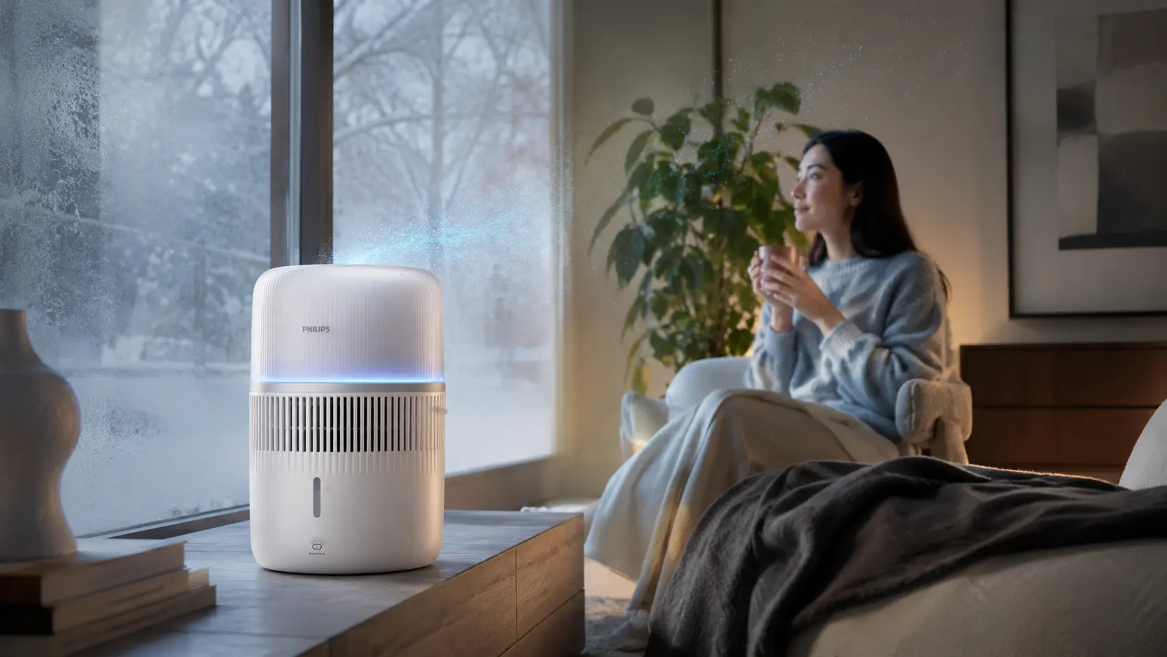 Woman relaxing beside a Philips humidifier on a winter day